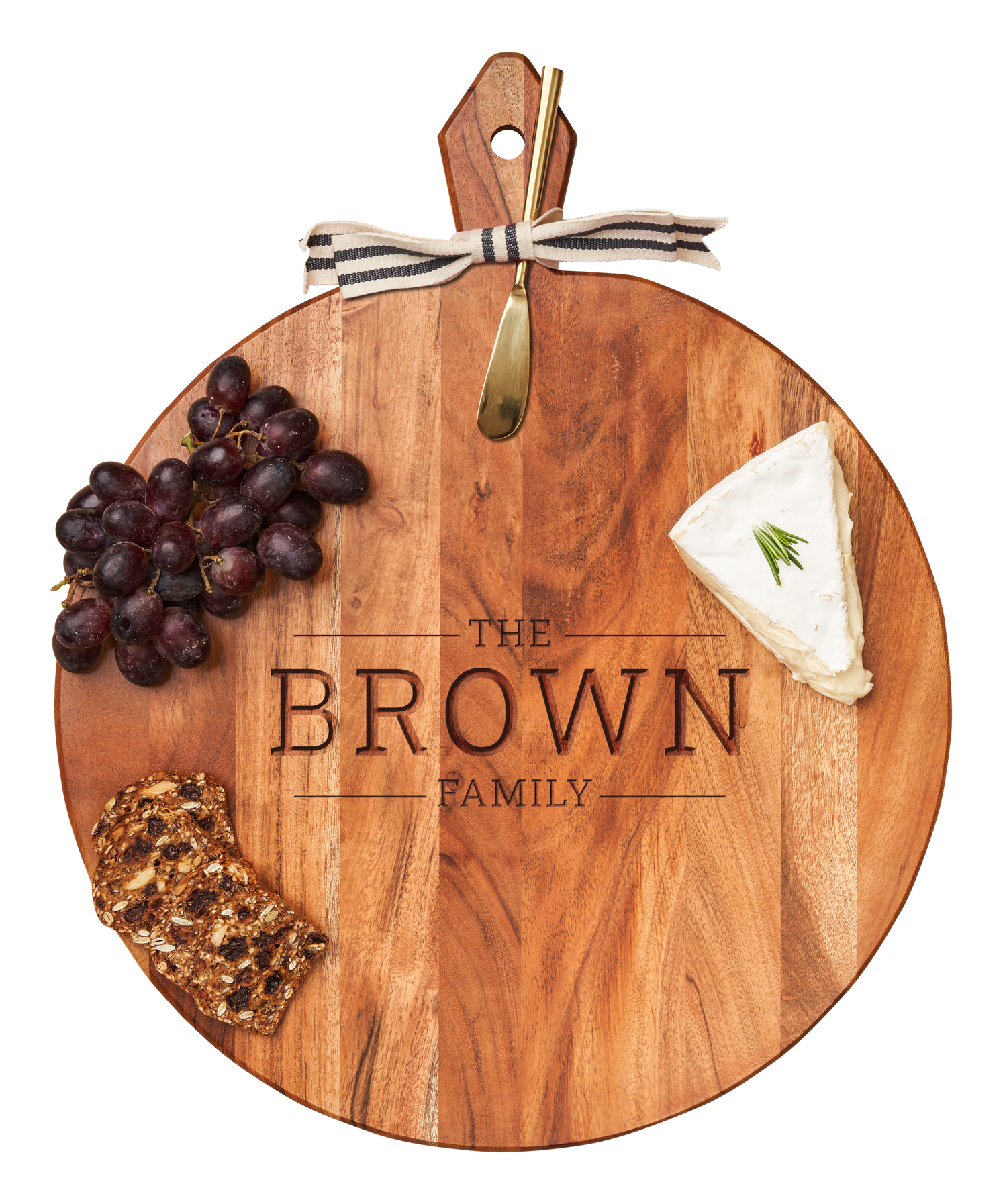Wooden cutting board with engraved 'The Brown Family' and food items on a white background