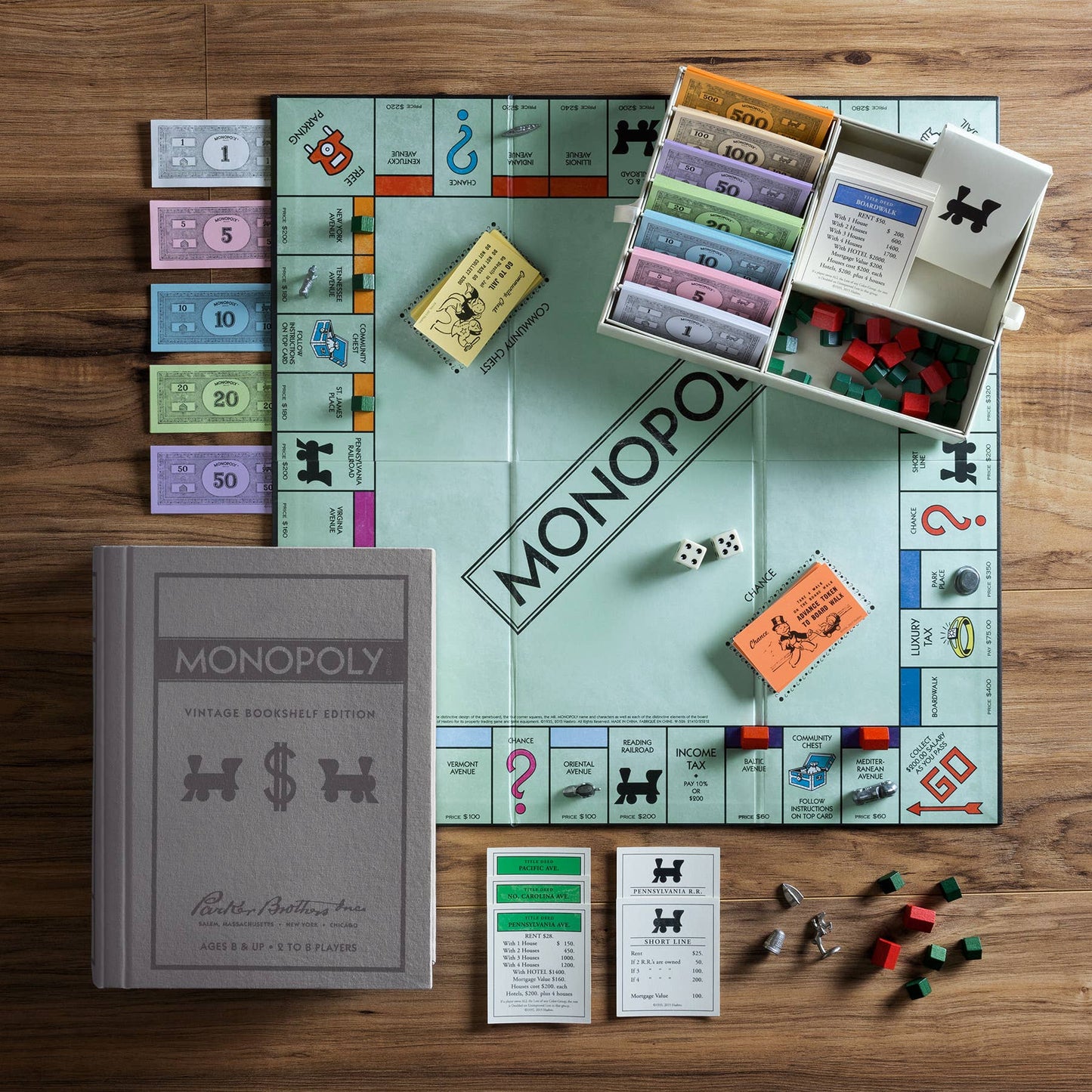 Monopoly board game set up on a wooden table with pieces and cards.