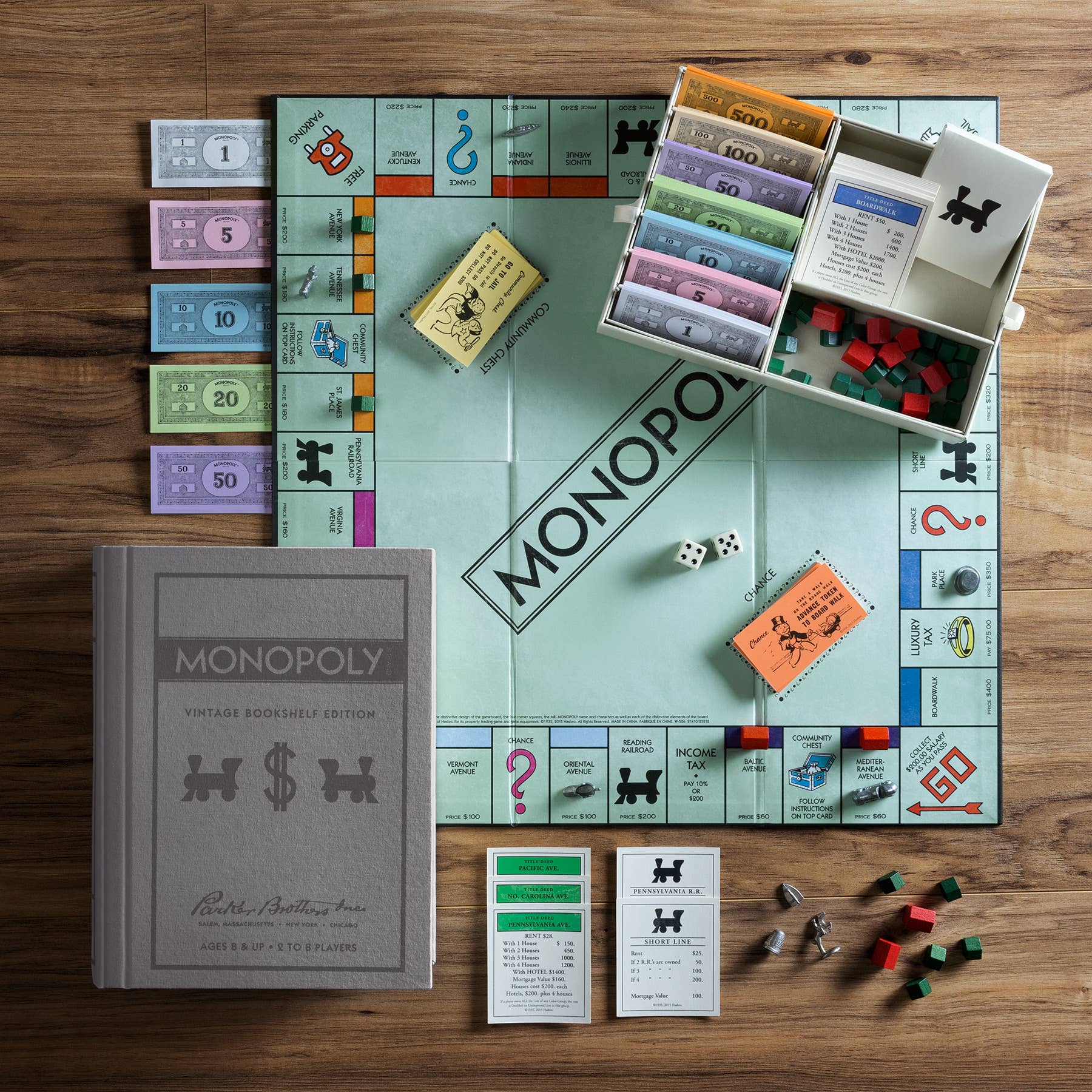 Monopoly board game set up on a wooden table with pieces and cards.