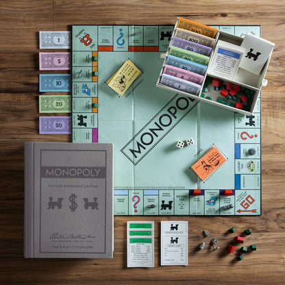 Monopoly board game set up on a wooden table with pieces and cards.