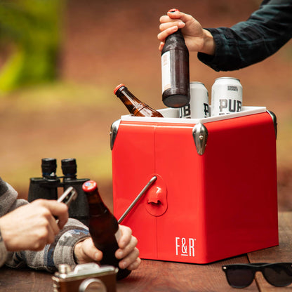 Red cooler box with drinks being opened by people outdoors