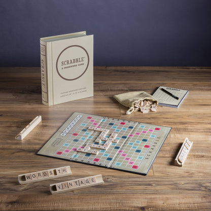 Scrabble game set up on a wooden table with a Scrabble book and tiles.