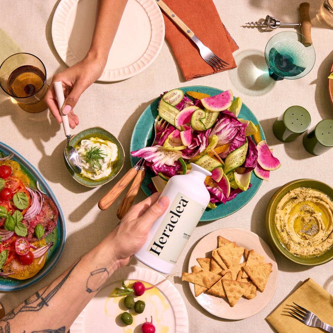 Table setting with a variety of dishes including a bottle labeled 'Heraclea'.