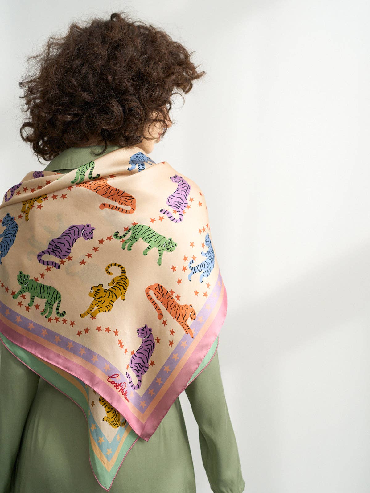 Person wearing a colorful tiger-patterned scarf on a plain background