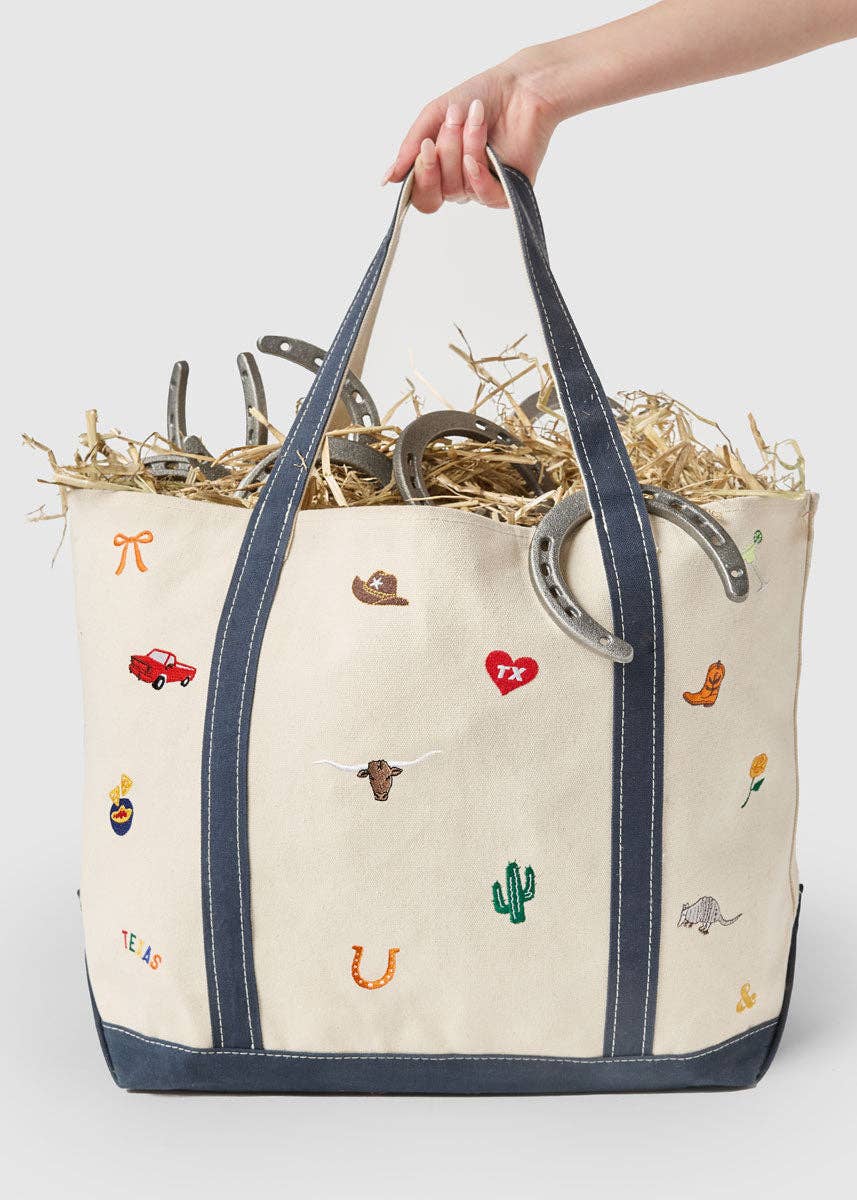 Tote bag with embroidered designs held by a hand on a white background