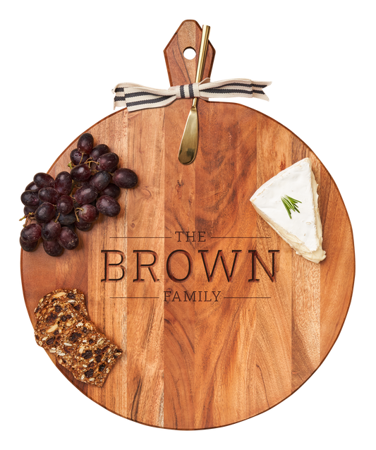 Wooden cutting board with engraved 'The Brown Family' and food items on a white background