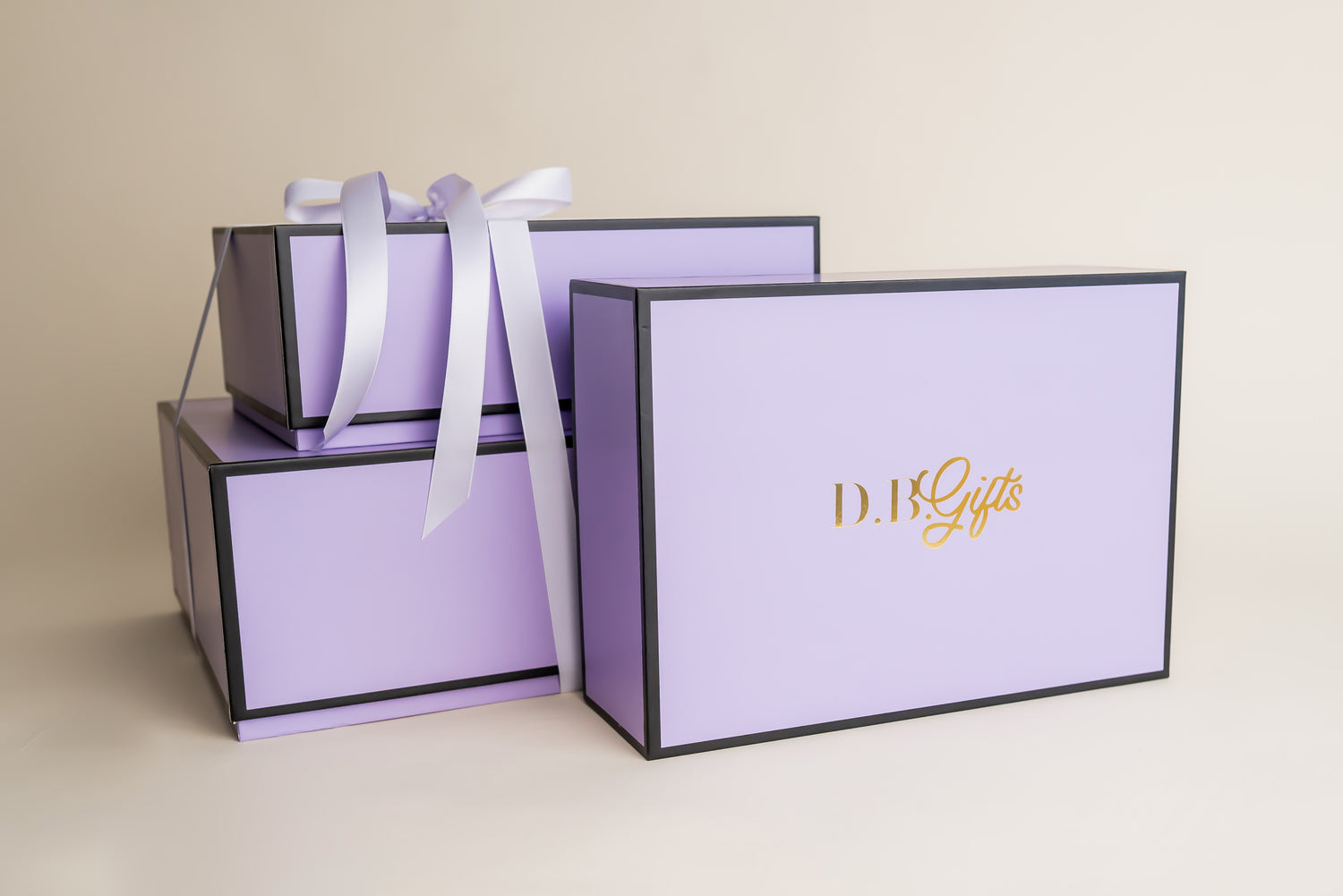Set of purple gift boxes with a white ribbon on a beige background