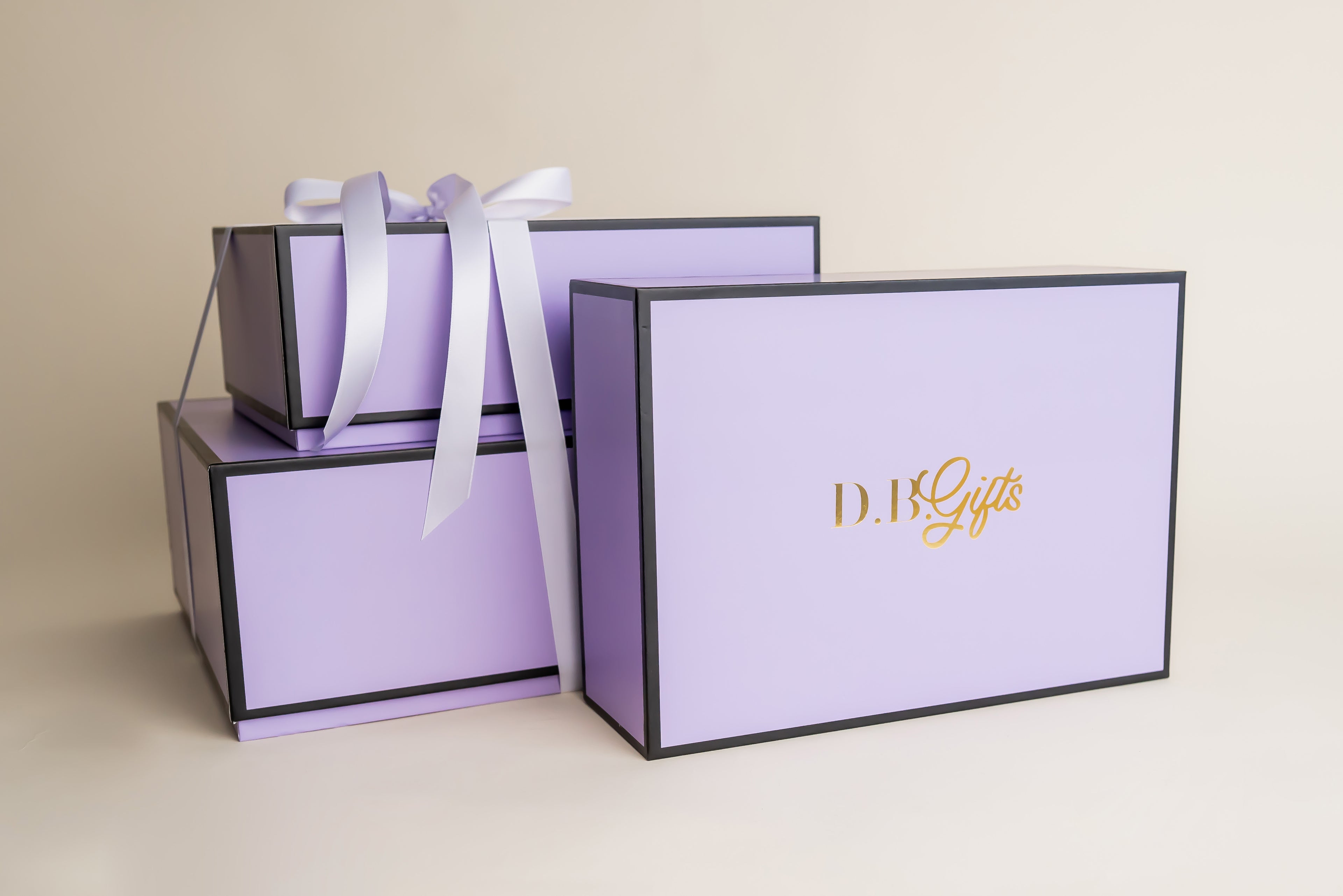 Set of purple gift boxes with a white ribbon on a beige background